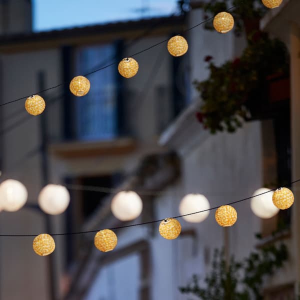 Grilandas luminosas LED penduradas na rúa dunha cidade ao anoitecer. As grilandas luminosas están acesas.