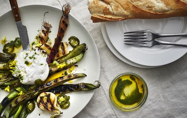 Grilled vegetables, oil and bread on white plates.