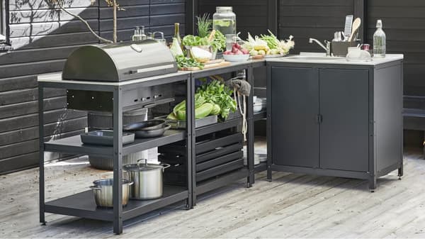 מנגל פחם חיצוני של GRILLSKÄR ואי מטבח מנירוסטה שחורה עם אביזרי צלייה ובישול.