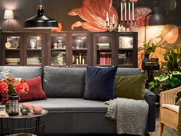 GRIMHULT sofa in a dramatically lit living room decorated with plants and flowers and various lamps.