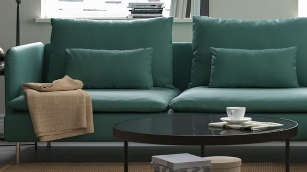 Grön SÖDERHAMN soffa placerad i ett ljust vardagsrum med lågt runt soffbord.