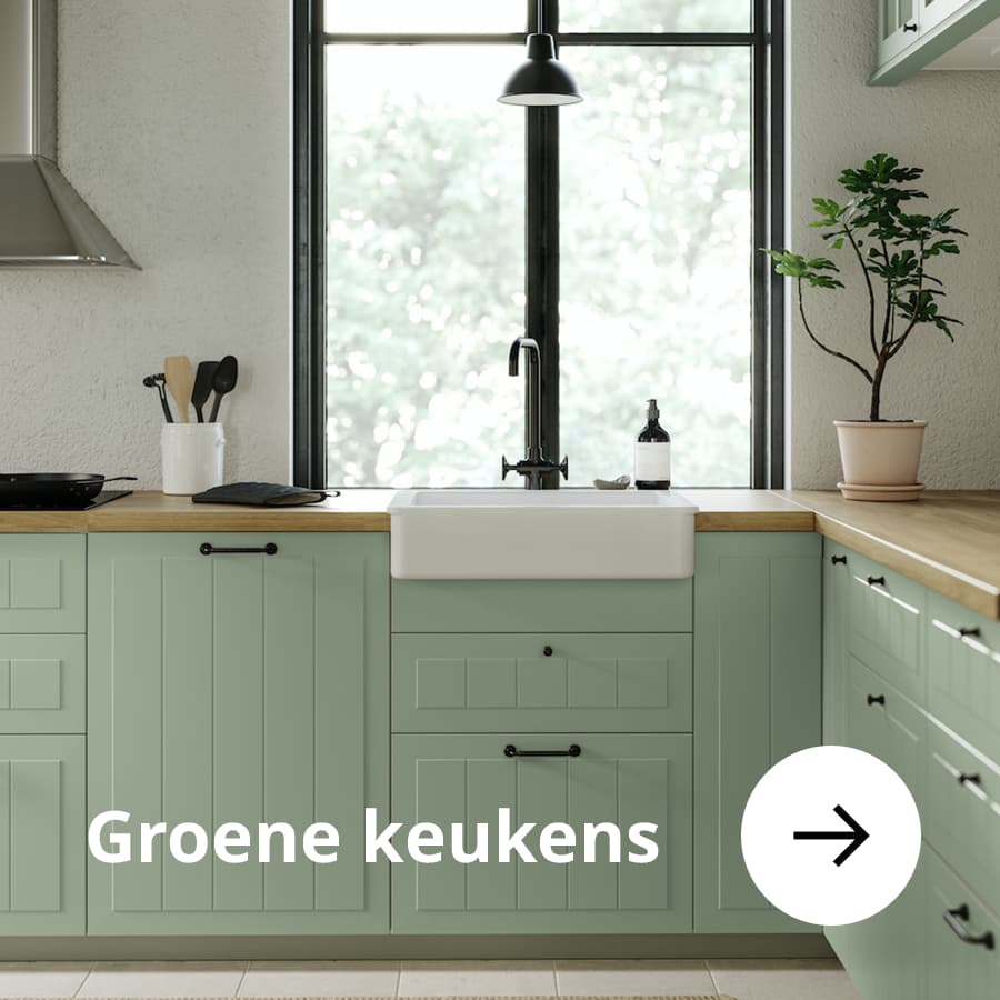 Groene keuken met een witte wastafel en een zwarte kraan.