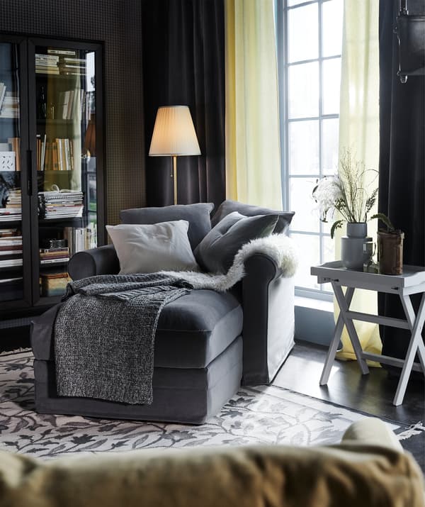 นอนขดตัวอยู่ในโซฟาพร้อมที่เท้าแขน GRÖNLID/เกรินลีด มาพร้อมกับปลอกสีเทาจากผ้าทัลล์มือราและหมอนอิงที่จะอยู่ในที่ที่คุณต้องการ