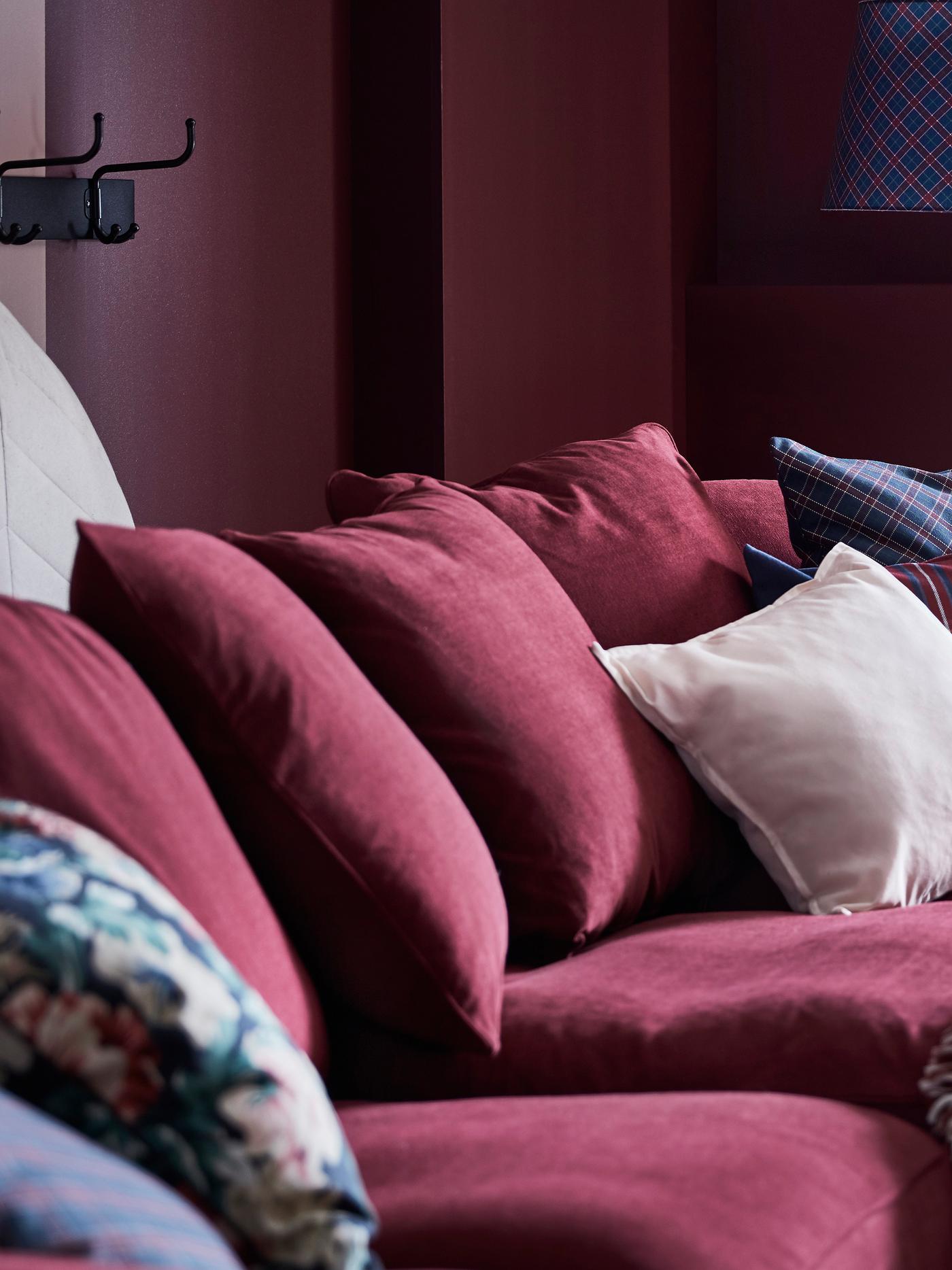 GRÖNLID dark red sofa furnished with SANELA pink and yellow cushions.