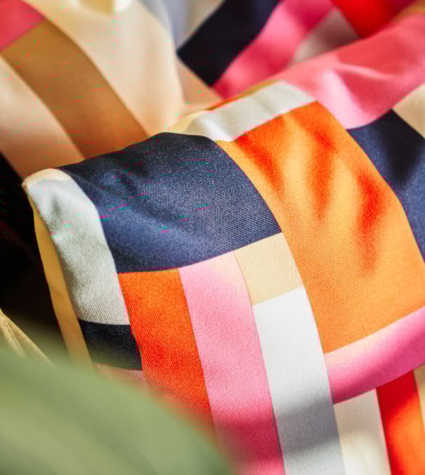 Gros plan de coussins colorés posés sur un fauteuil.