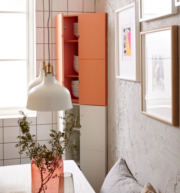 Gros plan de l’armoire d’angle IKEA PS, remplie de vaisselle blanche. 