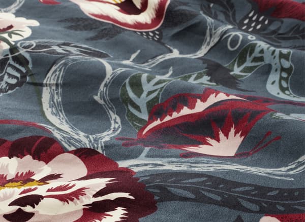 Gros plan de linge de lit à fleurs, en gris et bordeaux.