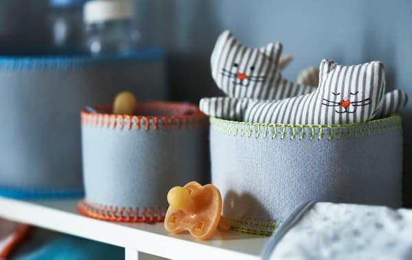 Gros plan de rangements en feutrine pour les affaires de bébé, telles que sucettes et hochets en forme de chat