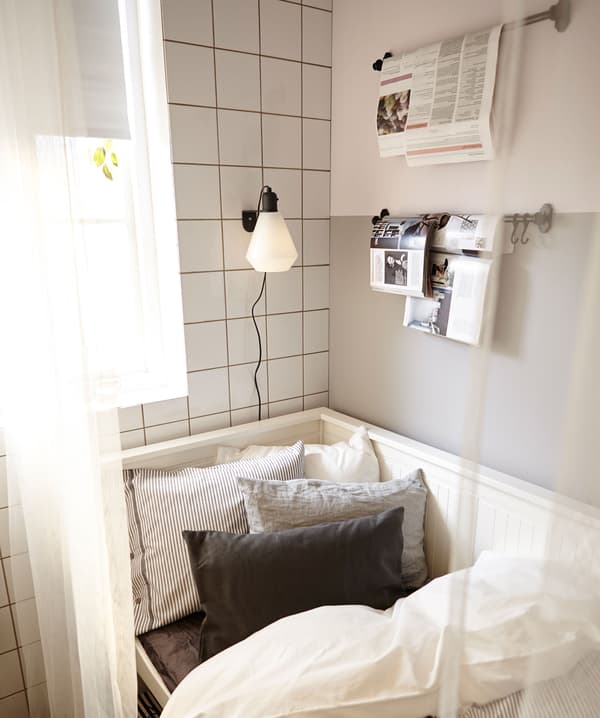 Gros plan du convertible, en mode lit. Le rideau est tiré pour faire office de séparateur et des magazines sont accrochés à des rails.