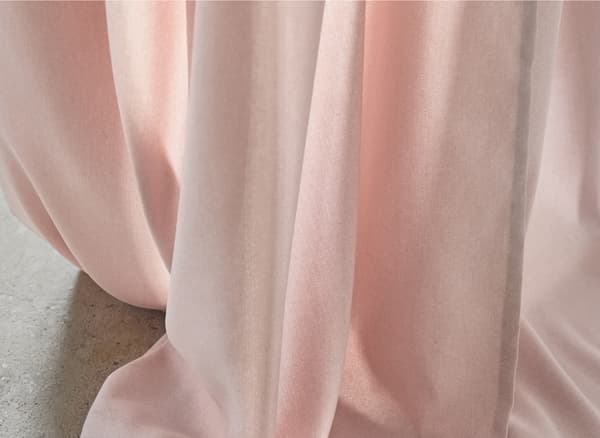 Gros plan du tissu d’un rideau rose.