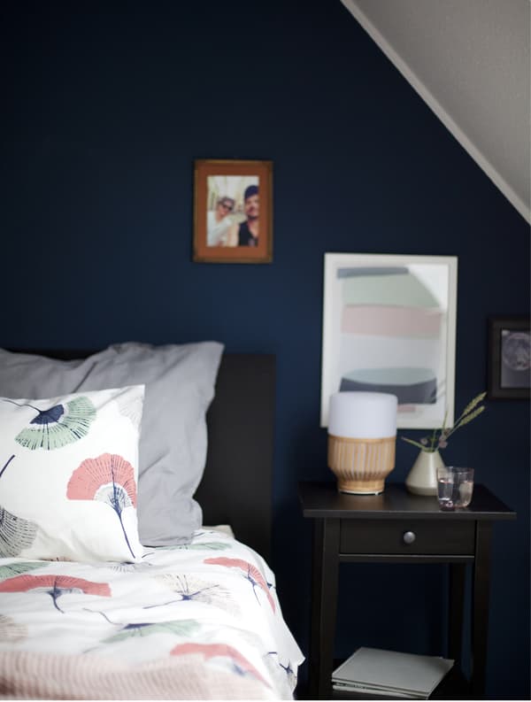 Gros plan d’un côté du lit, avec lampe et cadres au mur.