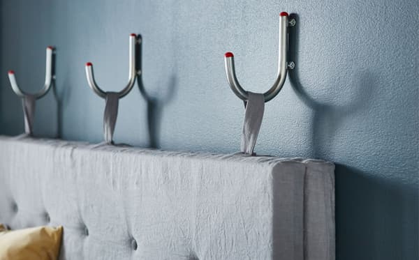 Gros plan d’un dossier de canapé fixé à trois crochets muraux.