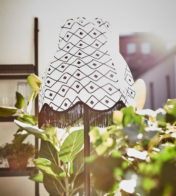 Gros plan d’un lampadaire à énergie solaire entouré de plantes vertes sur un balcon.