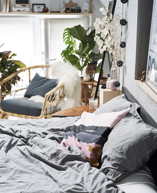 Gros plan d’un lit, avec fauteuil à l’arrière-plan.