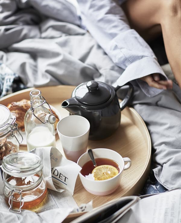 Gros plan d’un plateau rond avec théière, mugs et bocaux.