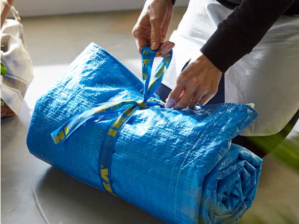 Gros plan d’une couverture de pique-nique roulée, confectionnée avec des sacs bleus IKEA et des torchons de cuisine