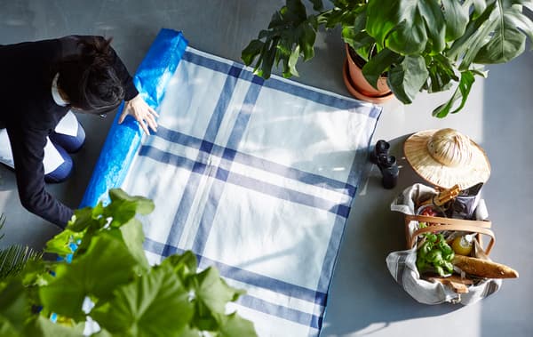 Gros plan d’une couverture de pique-nique roulée, confectionnée avec des sacs bleus IKEA et des torchons de cuisine