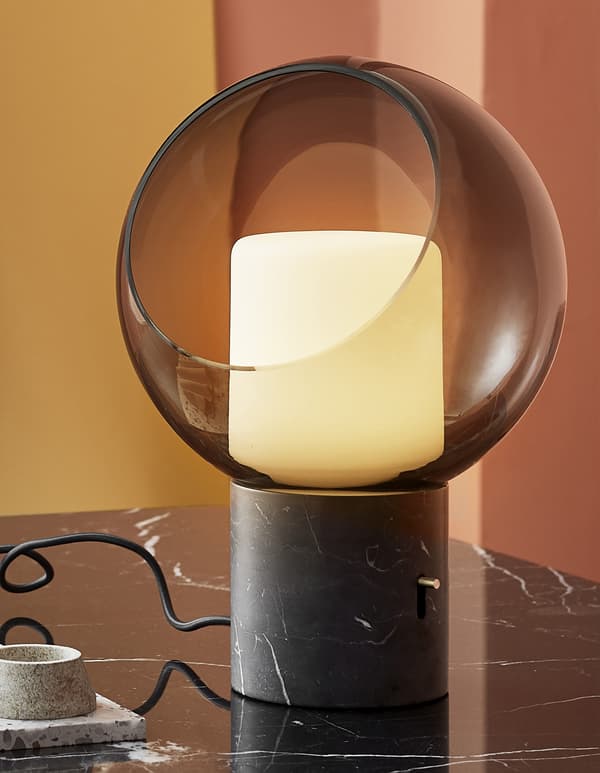 Gros plan d'une lampe de table avec globe en verre et pied en marbre.