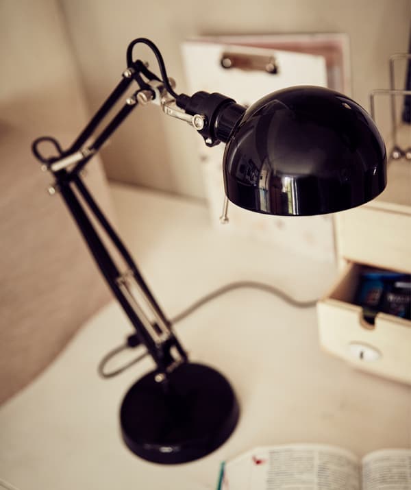 Gros plan d’une lampe noire sur un bureau blanc.