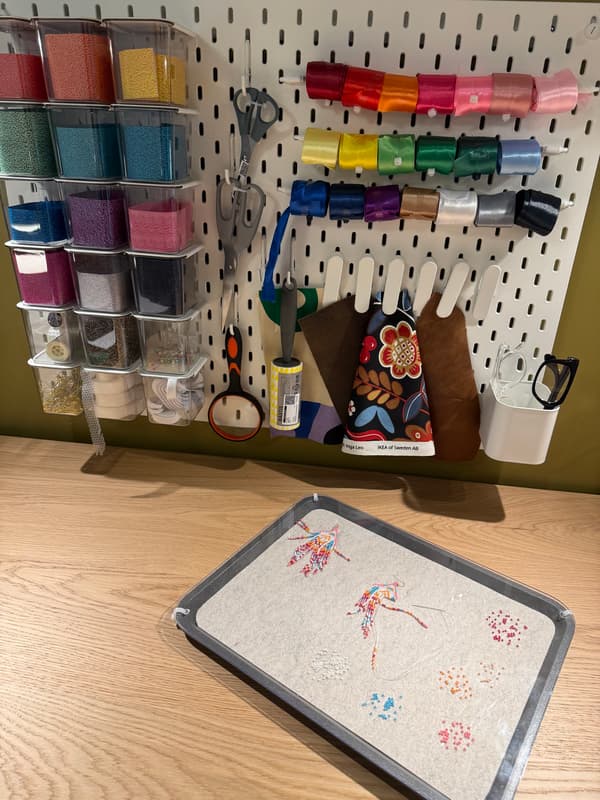 Gros plan sur un panneau perforé SKADIS blanc contenant des accessoires de bricolage colorés. 