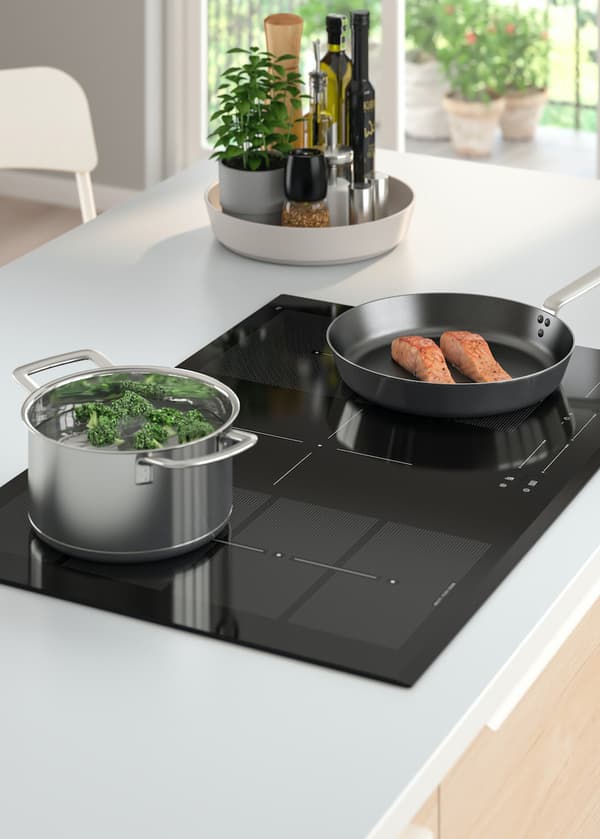 Gros plan sur une plaque de cuisson à induction BLIXTSNABB installée dans un îlot de cuisine. 