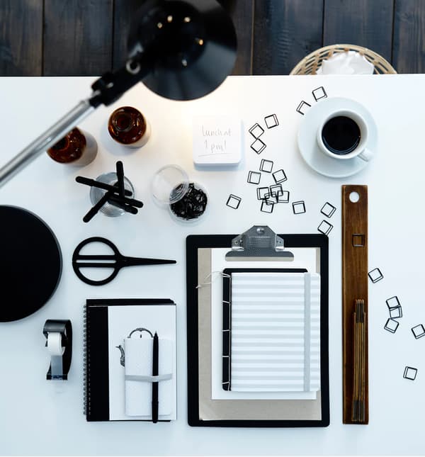 Gros plan sur une table de travail présentant quantité d’accessoires de bureau, tels que des carnets, des ciseaux et des attache-feuilles.