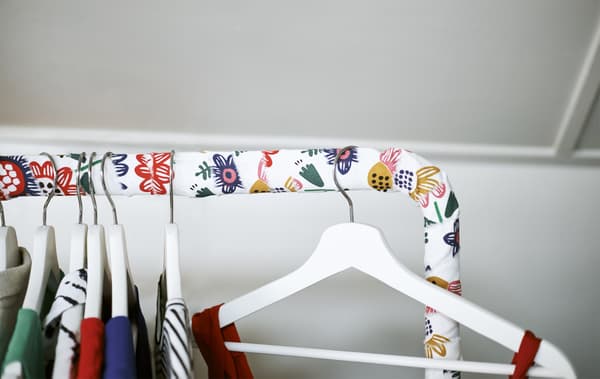 Gros plan sur une tringle à vêtements recouverte de tissu, avec des vêtements sur des cintres.
