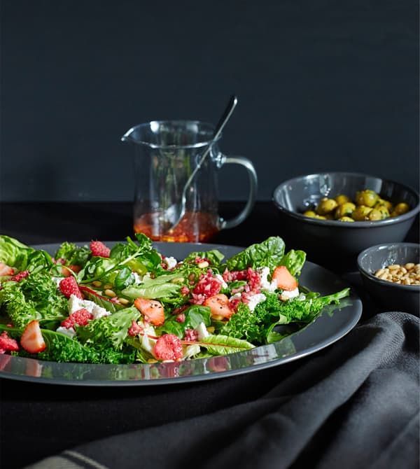Grosse salade posée sur une table avec d’autres assiettes garnies.