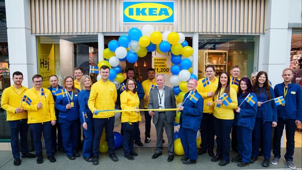 Group of IKEA co-worker in front of the entrance of IKEA Stockport. In the middle two people holding a ribbon.