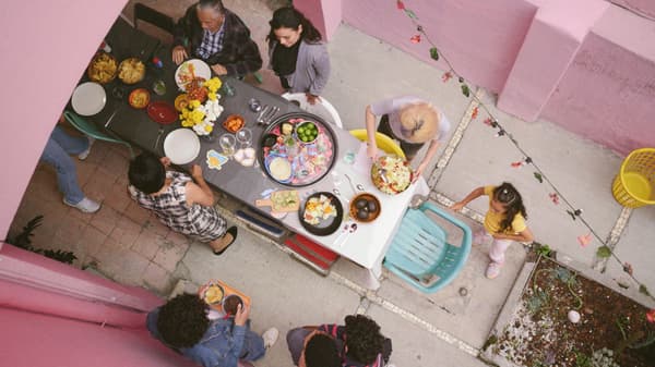 Group of people gathered around a set table, socializing and getting ready to enjoy dinner
