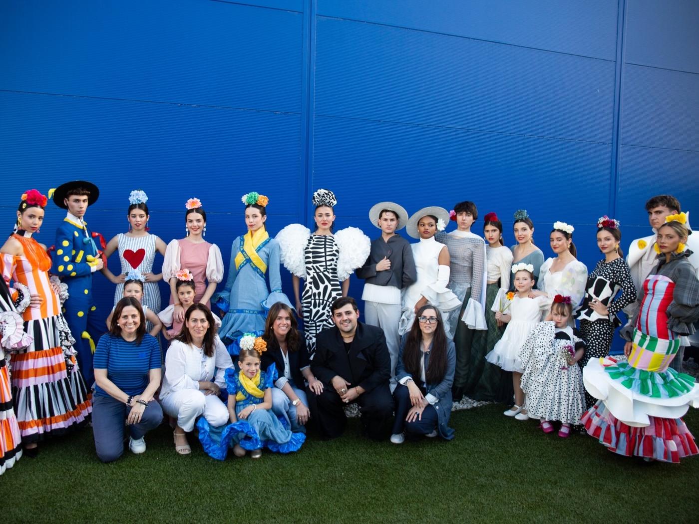 Grup de participants del Certamen de Moda Flamenca d’IKEA Sevilla posant davant d’una paret blava, amb vestits de flamenca creatius fets amb materials de la botiga.