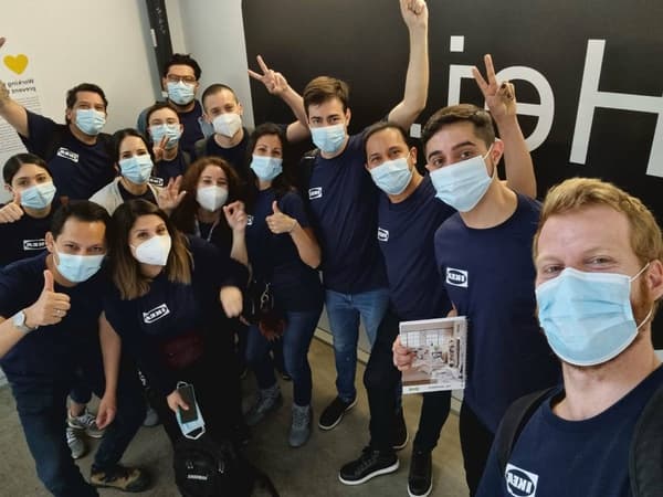 Grupo de colaboradores de IKEA usando la polera azul, mascarillas y saludando.