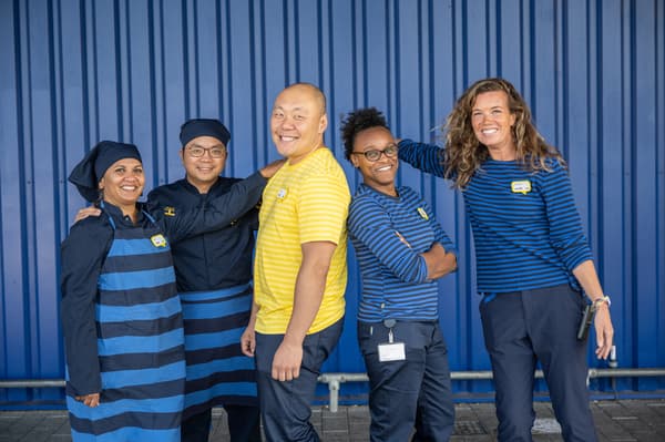 Gruppenbild von fünf IKEA Mitarbeiter:innen vor einer blauen Wand