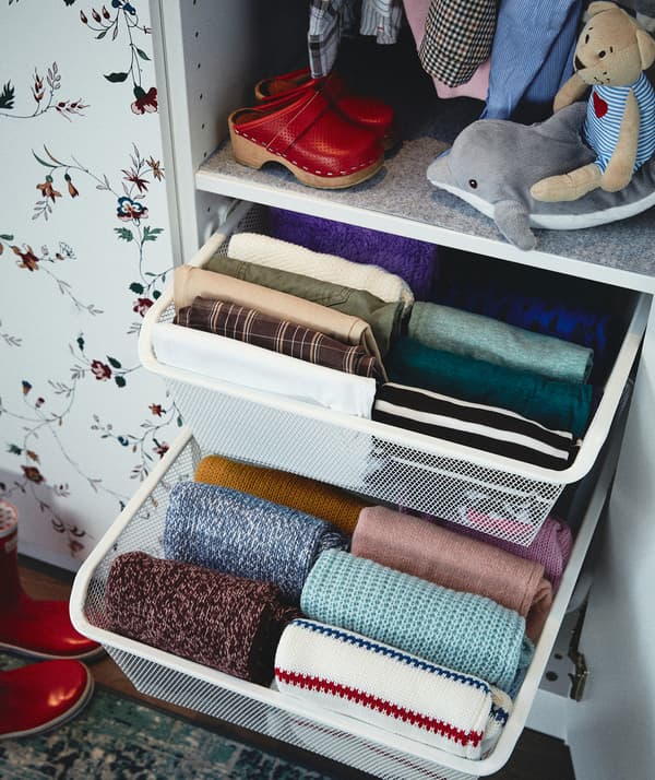 Guardaroba con due cassetti aperti pieni di capi piegati ordinatamente e organizzati in file - IKEA