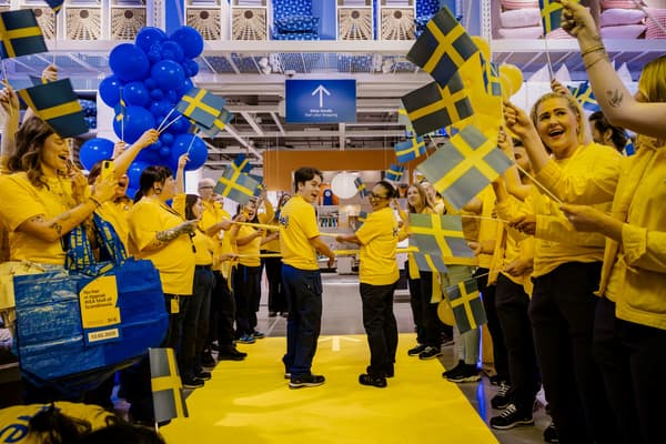 Gulklädda IKEA-medarbetare med flaggor  redo att klippa bandet för att öppna