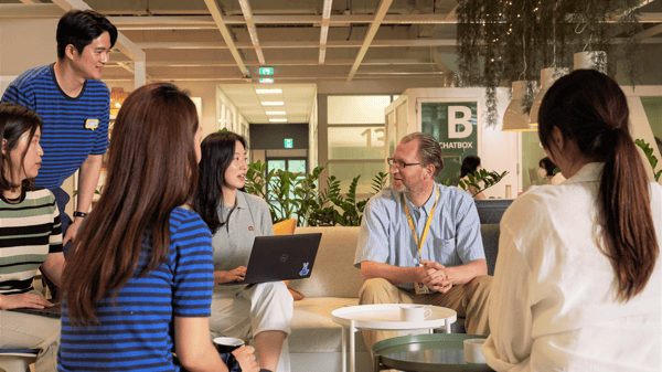 グリーンの多いオフィスラウンジで、ソファに座ったイケアのコワーカーたちがノートパソコンを囲み、ミーティングをしている様子。