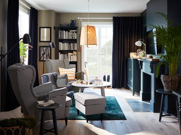 グレーのソファとラタンチェアを置いた落ち着いたリビング。黒いカーテンでモダンな雰囲気。