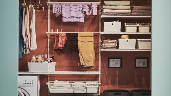 Gut organisierter Wäschebereich mit Regal, Körben, gefalteten Handtüchern und hängender Kleidung - links eine Waschmaschine - BOAXEL System.
