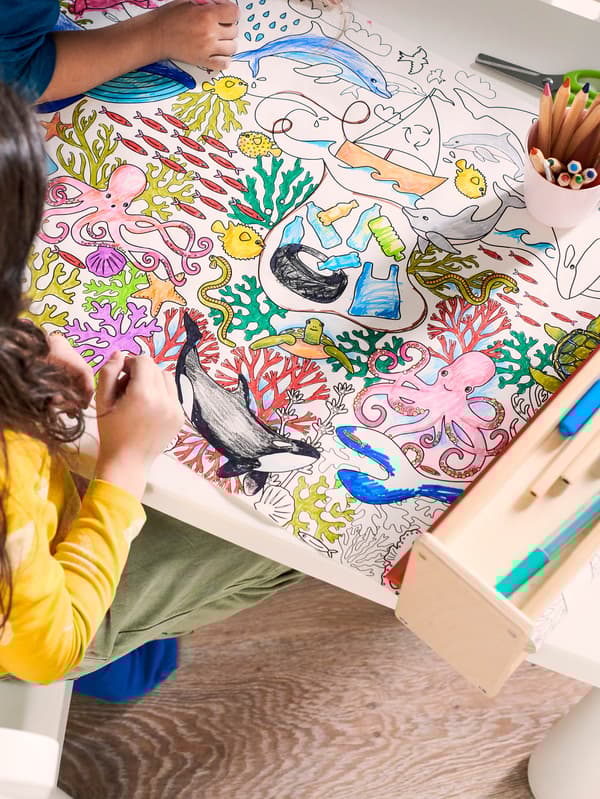 Gyerekek, akik éppen MÅLA színes ceruzákkal színezik ki a nagy méretű színezőt.