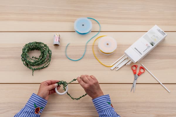 Hände wickeln die Drahtgirlande um den Ring.