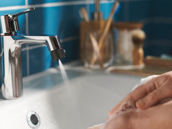 Händer som tvättas i tvål under en vattenkran