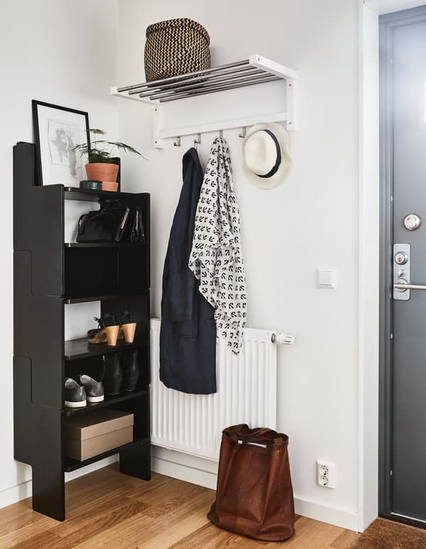Hall d'entrée parfaitement rangé, avec étagère, tablette et crochets auxquels pend juste l'un ou l'autre vêtement d'extérieur.