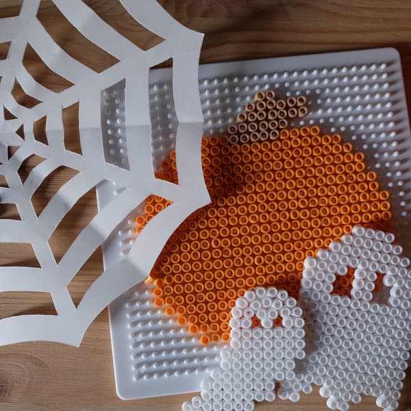Halloweenpyssel med pärlor som ska likna en pumpa och två spöken. 
