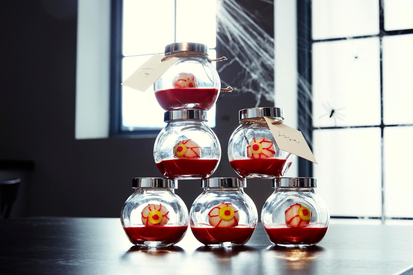 Halloweensnacks i form av ögon ligger i små burkar som är stablade på varandra.