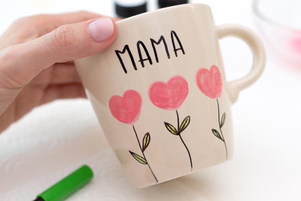 Hand hält die bemalte Tasse.