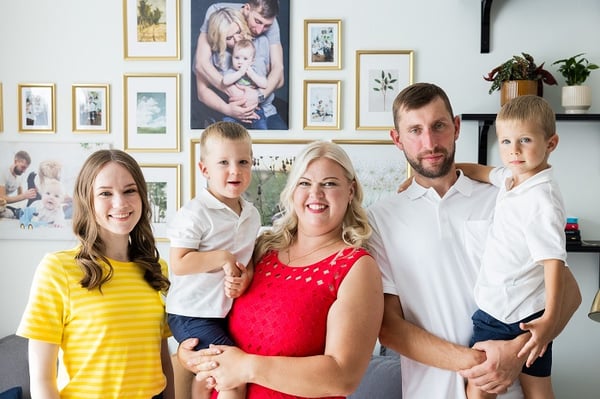 Happy family portrait with parents and children standing together in a bright living room interior