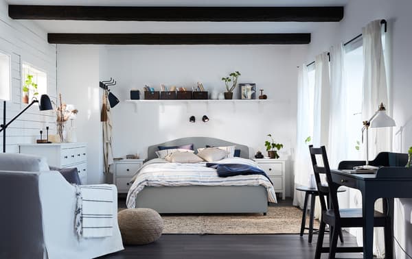 베이지 색상의 HAUGA 하우가 침대와 화이트 암체어, 블루그린 톤의 책상이 있는 클래식하고 조화로운 스타일의 침실