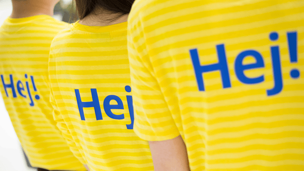 Hej！と書かれたイケアの制服を着た人が3人、背中を向けている