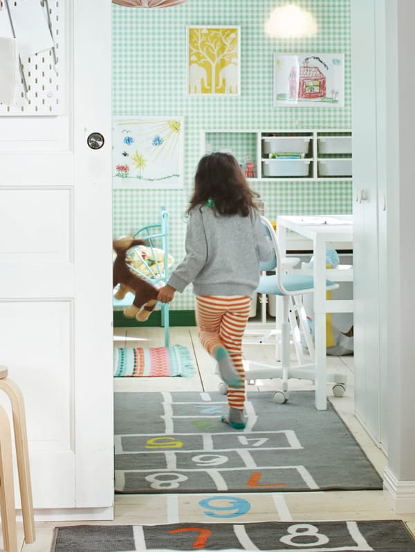 HEMMAHOS szőnyegen ugróiskolázó kislányt látunk.