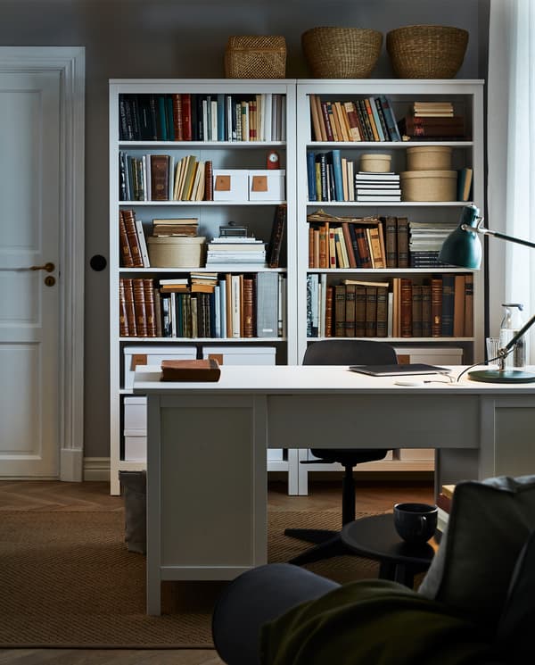 HEMNES 헴네스 책상이 있고 뒤쪽의 가까운 거리에 책상과 어울리는 책장에 책, 수납함, 장식용 수납함이 놓여 있는 방.